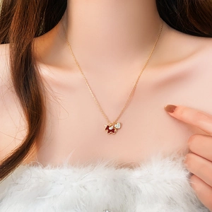 Detail of gold-plated necklace featuring a red enamel dog and crystal heart on a female neck