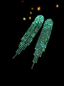 Macro shot of luxurious green rhinestone long tassel earrings over a dark background