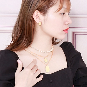 Layered gold textured oval pendant necklace set with elegant pearls on model