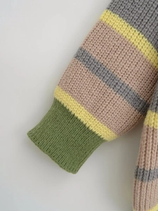 Detail of waffle knit sweater cuff with colorful stripes and elastic ribbed finish