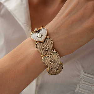 Close-up of vintage gold heart bracelet with embossed floral details on the wrist