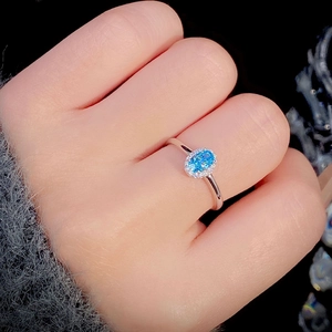 Elegant S925 sterling silver halo ring with oval sky blue gemstone worn on finger