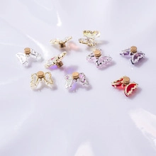 Detailed macro view of colorful mini metal butterfly nail art charms with gold edges