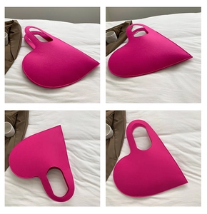 Detail of fuchsia heart-shaped felt handbag with cutout handle on minimalist background