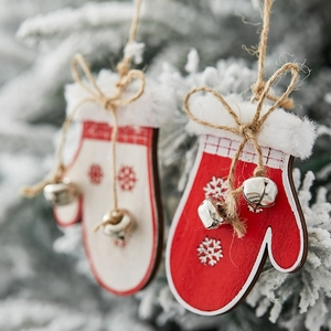 Christmas wooden glove ornaments with bells and snowflakes hanging on snowy pine branches