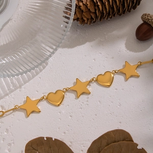 Gros plan d'un collier en acier doré avec pendentifs étoile et cœur sur fond texturé élégant