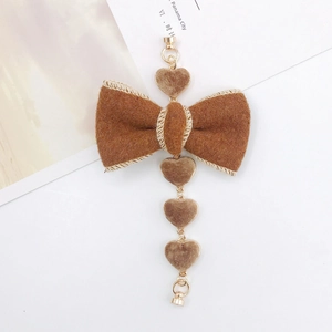 Detailed view of a brown plush bow pendant with four heart charms and metal rings