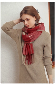 Detail of red and beige checkered wool-like scarf featuring soft tassel fringes on a model