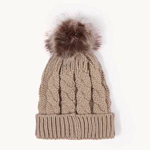 Close-up of brown cable knit beanie with faux fur pom-pom and ribbed cuff detail