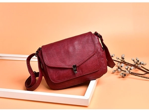 Detail of burgundy pebbled leather handbag with vintage metal clasp and flap closure