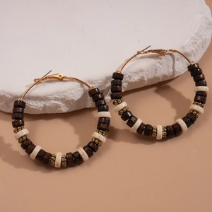 Bohemian large hoop earrings with wooden beads and gold metal accents on stone background
