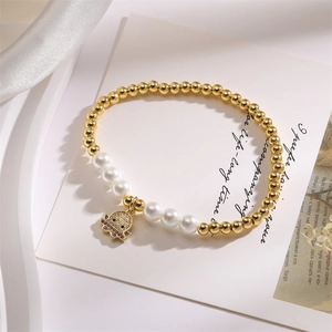 Detailed view of beaded bracelet featuring gold beads pearls and a red zircon octopus charm