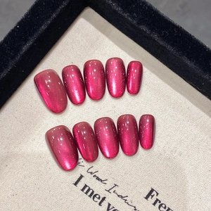 Vue détaillée de faux ongles faits main effet œil de chat magenta sur fond toile