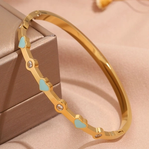 Dettaglio di bracciale in oro con cuori in smalto azzurro e pietre di zircone bianco