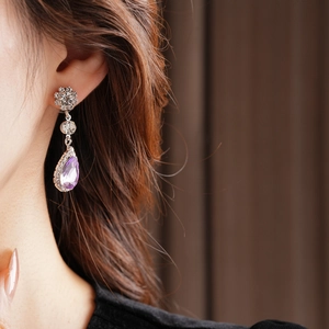 Detail of luxury waterdrop earrings with purple crystals on model in vintage style