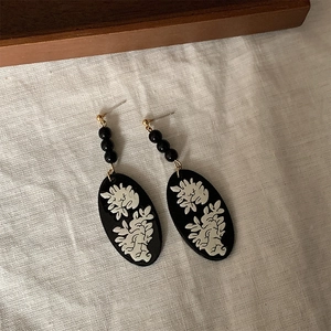 Vintage-Ohrringe in Schwarz mit weißem Blumenrelief und goldenen Steckern