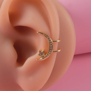 Gold star and moon ear cuff with cubic zirconia crystals on pink background