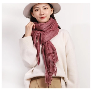 Detail of pink knitted scarf with decorative tassels worn by model on white background