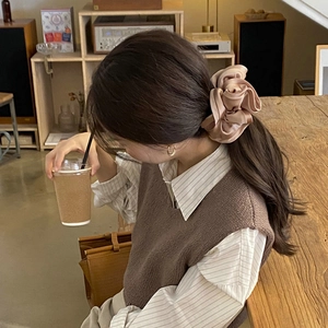 Close-up of a premium champagne satin scrunchie with elegant ruffled edges on a model