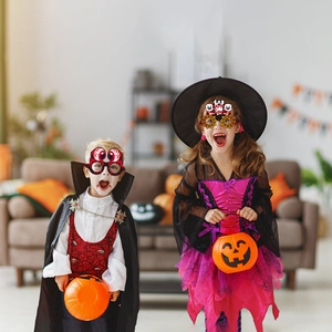 Kinder mit lustigen Halloween-Papierbrillen mit Kürbis- und Geistermotiven für Partyspass