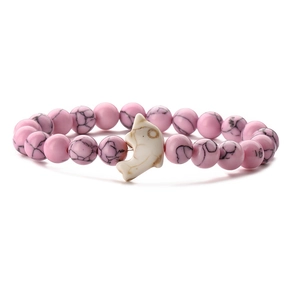 Close-up of pink textured beaded bracelet with a white dolphin charm on white background