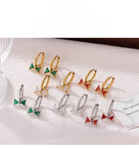 Detail of bow-shaped hoop earrings with emerald, white and ruby zircon stones
