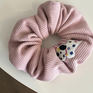 Close-up of pink knitted scrunchie with a cute cartoon animal patch and polka dots
