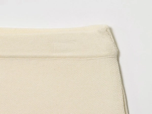 Macro detail of high-quality cream white knitted fabric with fine ribbed texture