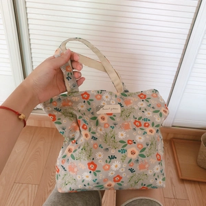 Floral cotton tote bag with vintage flower patterns and double handles held by hand