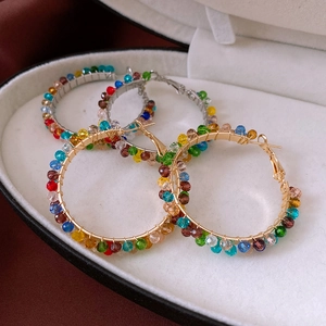 Macro detail of handmade rainbow bead hoop earrings with intricate gold wire wrapping