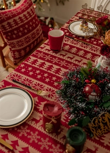 Detail of red and beige Christmas tablecloth featuring jacquard reindeer and snowflake patterns