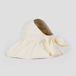 Dettaglio di un cappello da sole beige a tesa larga con fiocco decorativo per protezione