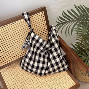 Canvas checkered tote bag with matching bear charm on a wicker chair with plants