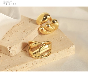 Detail showing multi-layer geometric copper rings on textured stone and silk