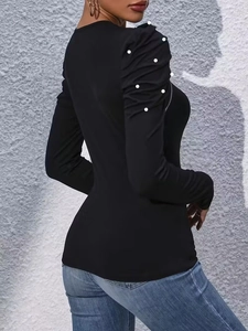Detail of elegant black long sleeve top with pearl accents and ruched shoulder design
