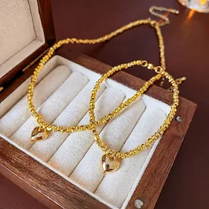 Elegant gold-tone jewelry set featuring a beaded necklace and bracelet with heart pendants