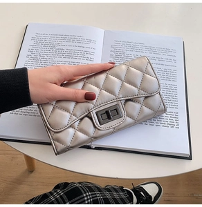 Macro detail of silver quilted diamond pattern wallet with dark metal twist lock on book