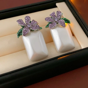 Gros plan de boucles d'oreilles vintage avec strass violets et perles blanches carrées