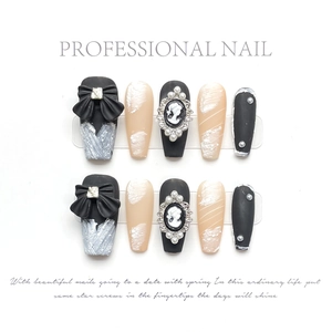 Detail of handmade press-on nails featuring black bows, cameo relief and pearl accents