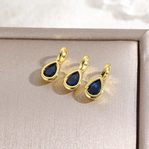 Detailed close-up of three gold 18k plated waterdrop pendants with blue zircon stones