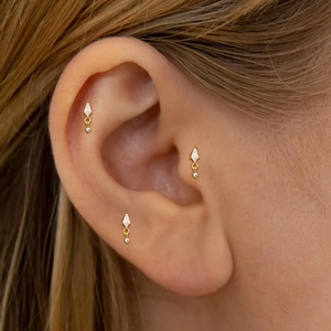 Close-up of three gold-plated S925 silver stud earrings with rhombus zircon on the ear