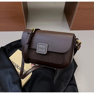 Detail of dark brown leather and suede crossbody bag with gold buckle and brand logo
