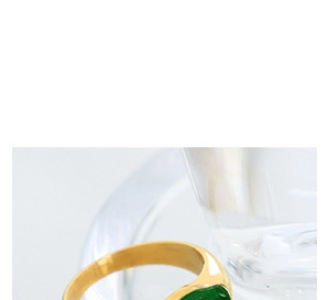 Detail shot of a gold metal ring featuring a green rhombus zircon in a clean setting