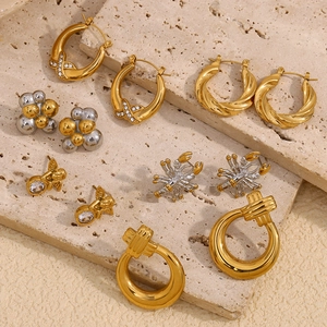 Detailed flat lay of geometric gold and silver earrings with zircon butterfly and crab motifs