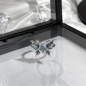 Detail of silver butterfly ring with blue marquise stones on white silk with ice decor
