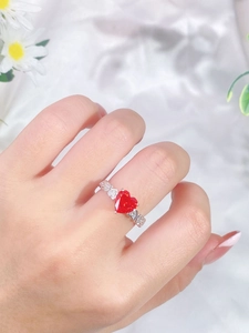 Macro detail of heart-shaped pink stone ring with openwork heart band on white silk