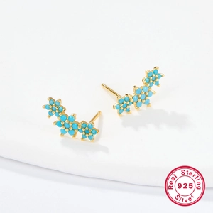 Macro shot of gold-plated S925 silver flower stud earrings with sky blue zircon stones