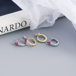 Detailed view of flower-shaped earrings with rose red stones and pave diamonds