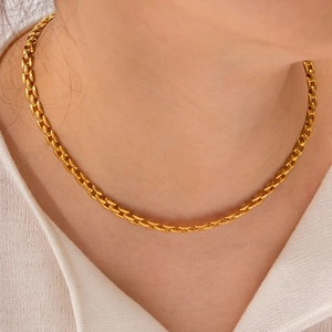 Gros plan d'un collier chaîne en acier titane plaqué or 18 carats sur une femme