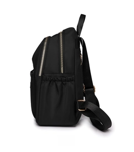 Detail view of black nylon backpack featuring gold zippers and side elastic pocket